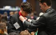 A person helps someone with their necktie.